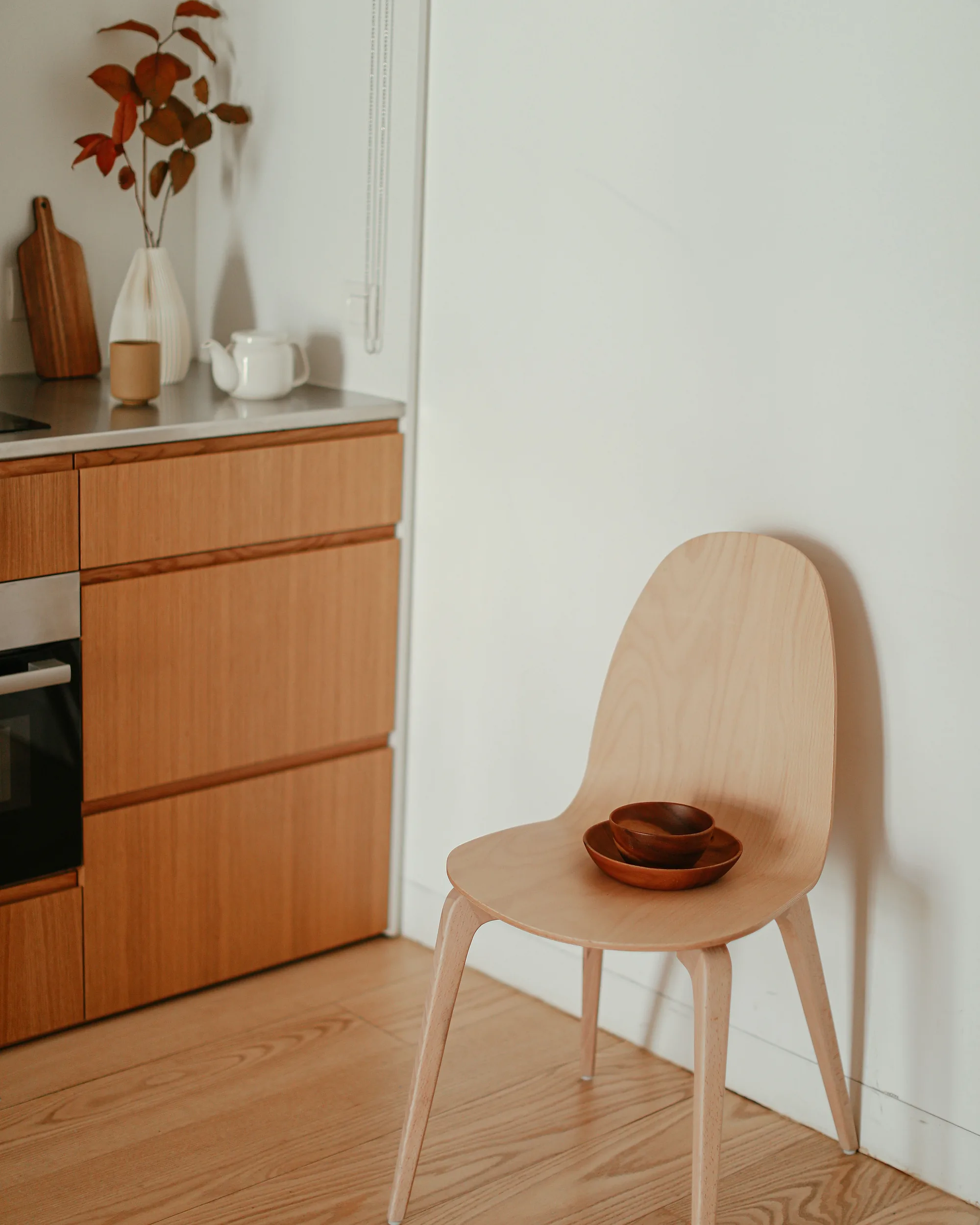 Sedia in legno chiaro accanto a una cucina, con luce morbida